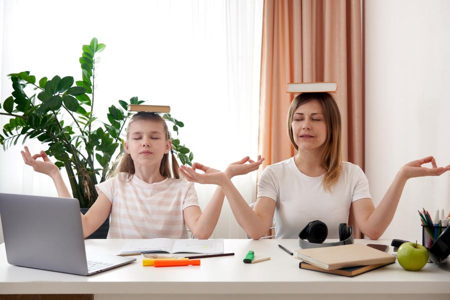 Женщина с ребенко держат книги на голове и концентрируются