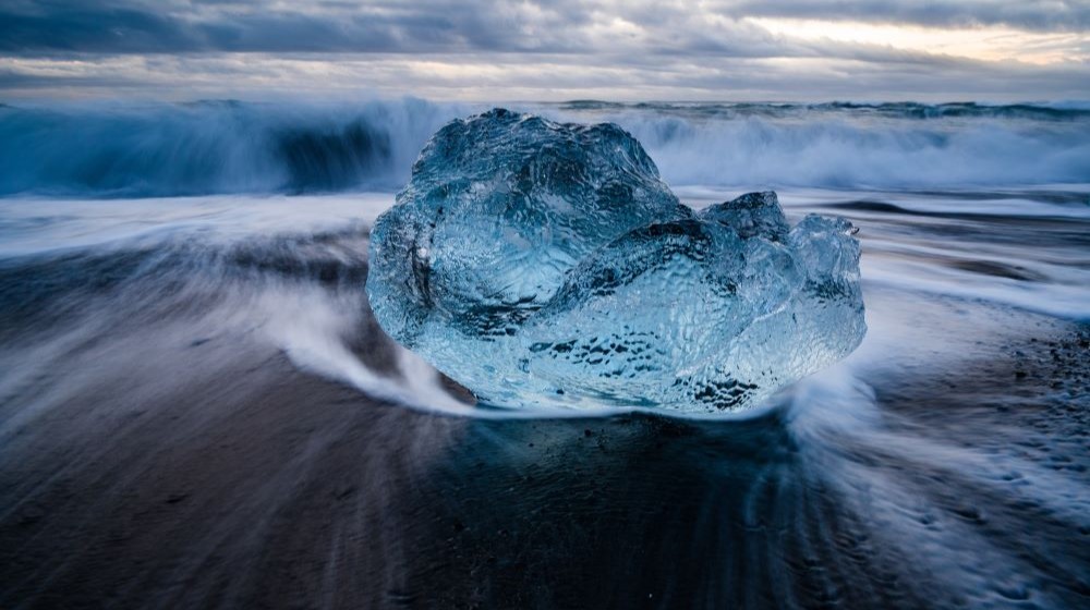 A large clear crystal lies on the seashore