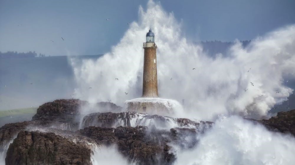 A huge wave hits the lighthouse