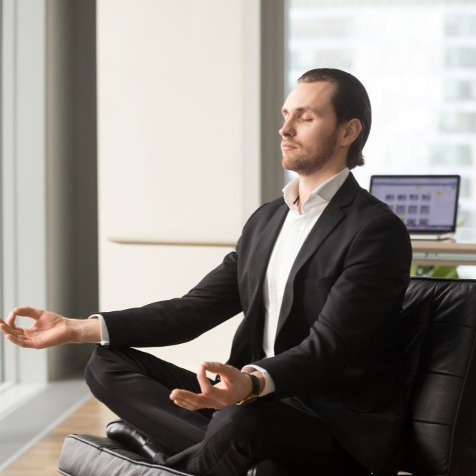 A successful businessman meditates in the workplace